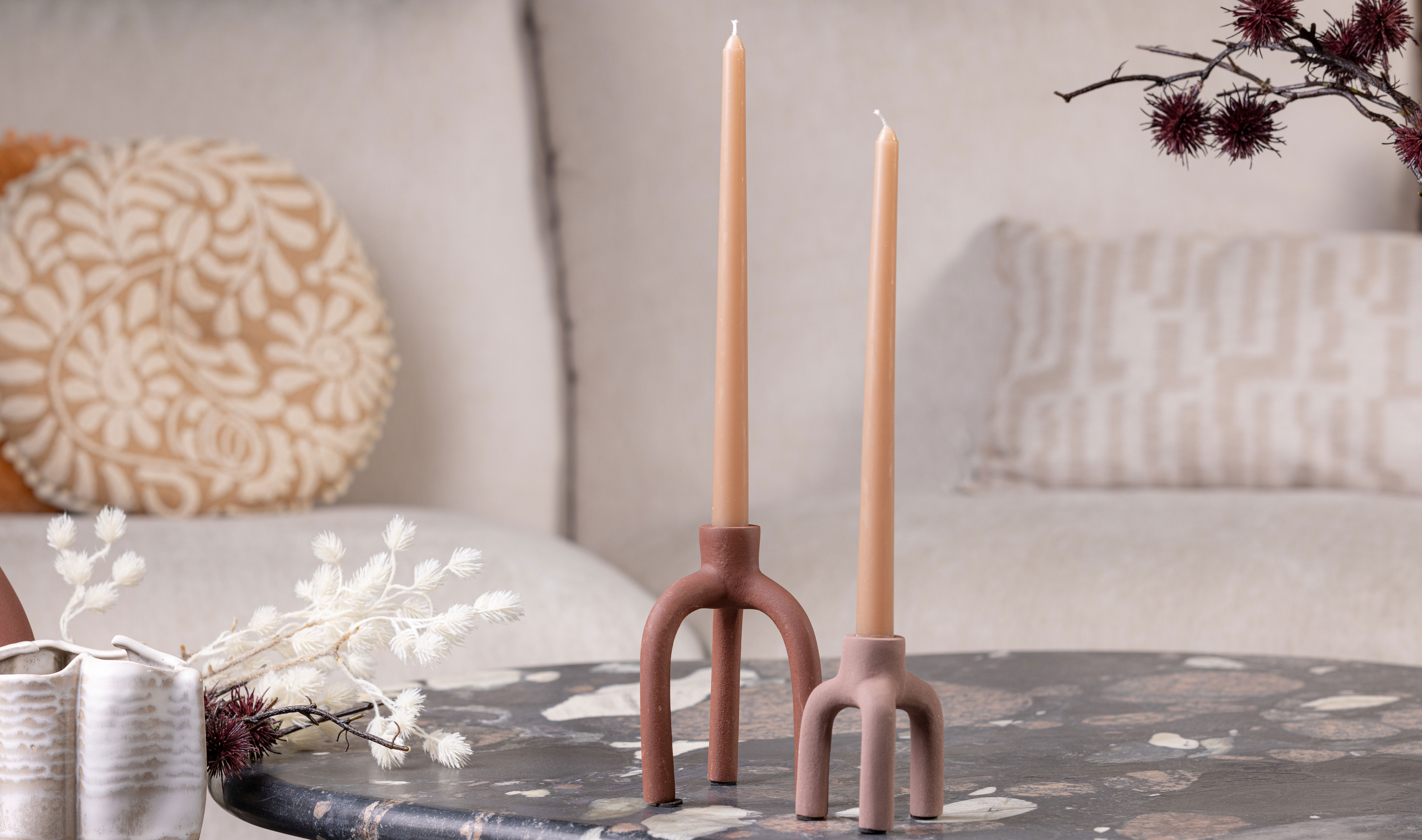 Minimalist candle holders with tall candles in warm neutral tones.